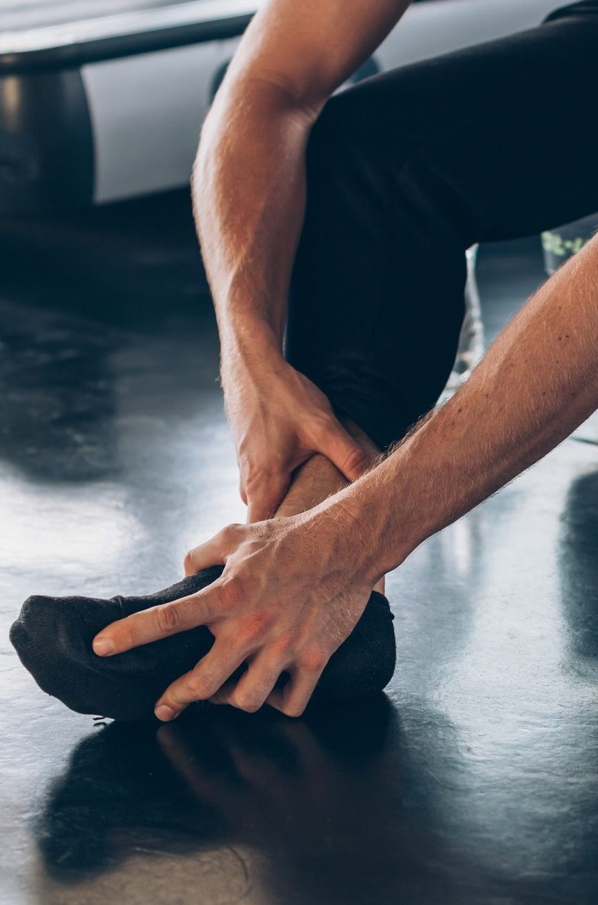 Male athlete suffering from ankle tendon ligament
